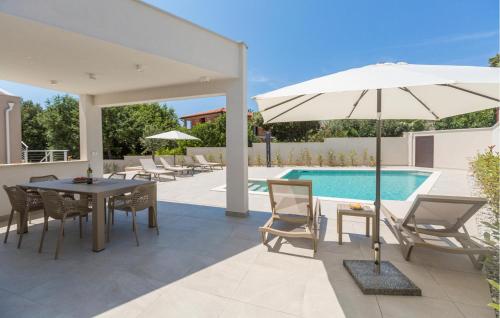 a patio with a table and an umbrella and a pool at Lovely Home In Barbariga With Wifi in Barbariga
