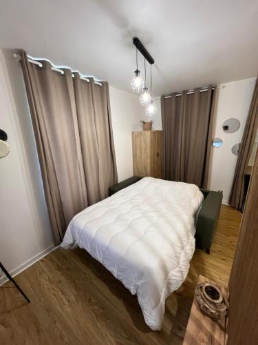 - une chambre avec un lit blanc et des rideaux dans l'établissement Très joli STUDIO en plein cœur d'ANGOULEME, à Angoulême