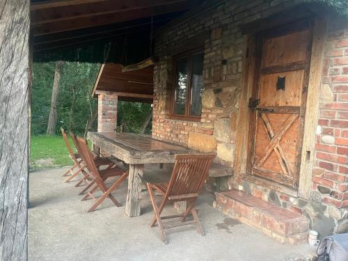 a wooden table and chairs outside of a cabin at Vikendica Drina Mladenova suma in Čajići