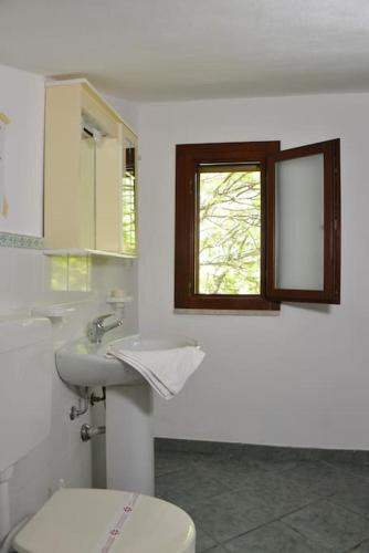 a bathroom with a toilet and a sink and a window at Ipsy by Penta Dream House in Campofelice di Roccella