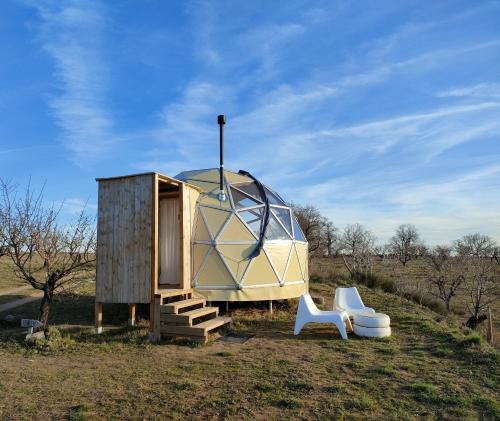 a dome tent and two white chairs in a field at Mirador de Pideago - Gratal y Nabiella in Bolea