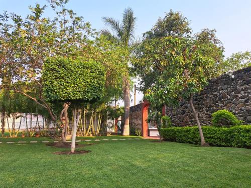 a garden with trees and a stone wall at Hotel Quinta Paraiso in Cocoyoc