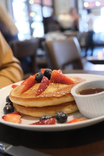 a plate of pancakes with fruit and a bowl of syrup at Library Hotel by Library Hotel Collection in New York