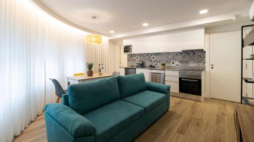 a living room with a blue couch and a kitchen at Stop & Relax - Parking in Porto