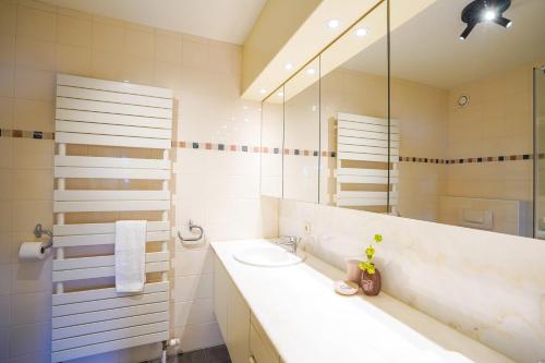 ein weißes Badezimmer mit Waschbecken und Spiegel in der Unterkunft Huswell - Apartment with sea view & terrace in Oostduinkerke in Koksijde