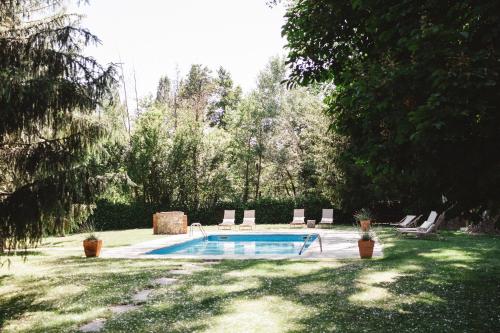 a swimming pool in a yard with chairs and trees at Mas Sant Marc in Puigcerdà