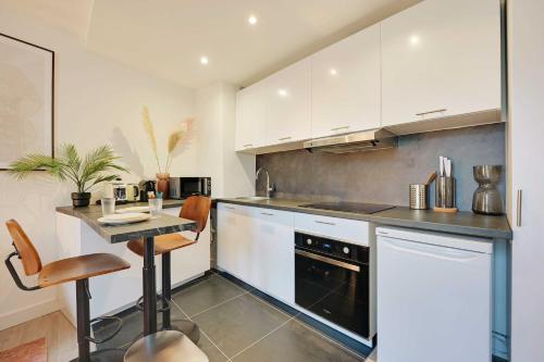 une cuisine avec des armoires blanches et une table à l'intérieur dans l'établissement Charming duplex - 1BR-2P - Le Marais, à Paris