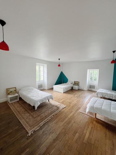 une grande chambre blanche avec deux lits et du parquet dans l'établissement Gîte des Lavandières en bordure de Vienne (Civaux), à Salles-en-Toulon
