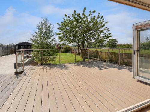 a large deck with a fence and a tree at Dolly's House in Sandbach