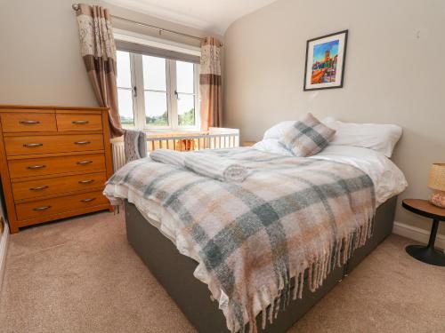a bedroom with a bed and a dresser and a window at Dolly's House in Sandbach