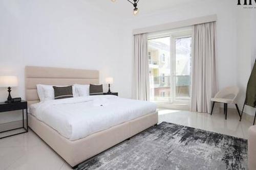 a white bedroom with a large bed and a large window at Gorgeous 2 Bed Apt in Al Warqa in Dubai