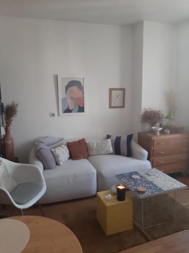 un salon avec un canapé blanc et une table dans l'établissement Cosy appartement, à Fontenay-sous-Bois