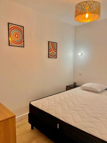 une chambre avec un lit et deux tableaux au mur dans l'établissement T2 1er LE VICTOR HUGO, à Cancale