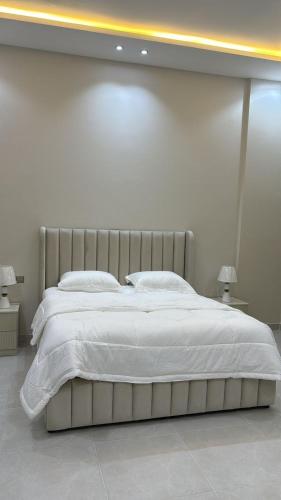 a bedroom with a large bed with white sheets and pillows at شقة غرفتين وصالة مدخل مستقل in Taif