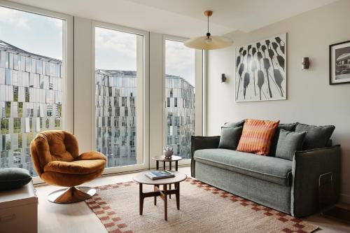 - un salon avec un canapé, une chaise et des fenêtres dans l'établissement Edgar Suites Lille - Shake, à Lille