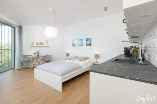 a white room with a bed and a kitchen at Pinea 620 - Easy - Rent Apartments VI piętro z widokiem na morze in Pobierowo