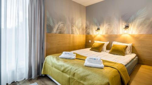 a bedroom with a bed with two towels on it at ENKLAWA Apartamenty Piamola in Krynica Morska