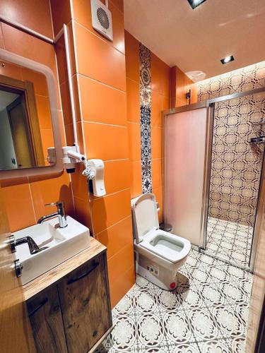 an orange bathroom with a toilet and a sink at Taksim REXXEE Istanbul Istiklal Hotel in Istanbul