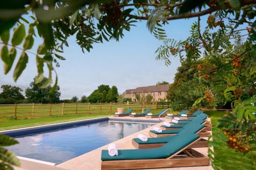 a row of lounge chairs sitting next to a swimming pool at The Barnsdale, Rutland in Oakham