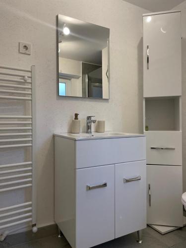 a white bathroom with a sink and a mirror at Aminah House in Constanţa