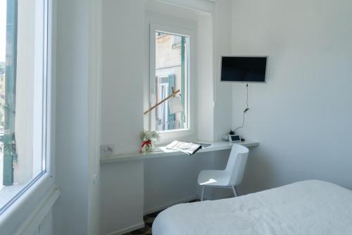 a white room with a bed and a desk and a window at About Italy Holiday Rooms and Apartments in Portovenere
