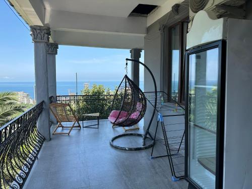 a porch with chairs and a hammock on a balcony at Horizon Hills - ჰორიზონ ჰილს in Kvariati