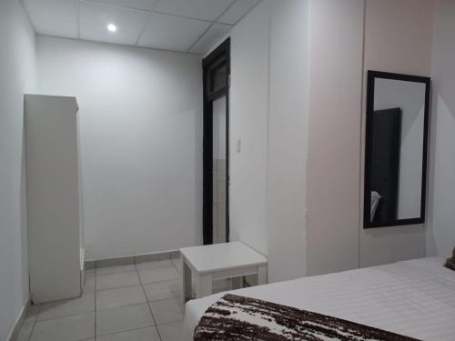 a white room with a bed and a mirror at De Bliss Lodge in Johannesburg