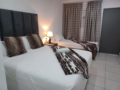 a bedroom with two beds and a lamp on a table at De Bliss Lodge in Johannesburg