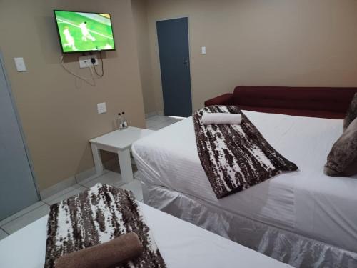 a room with two beds and a tv on the wall at De Bliss Lodge in Johannesburg