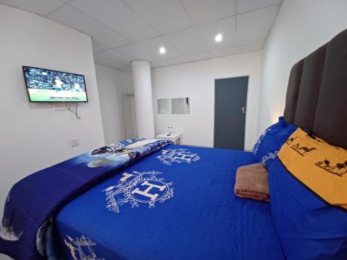 a bedroom with a blue bed with a tv on the wall at De Bliss Lodge in Johannesburg