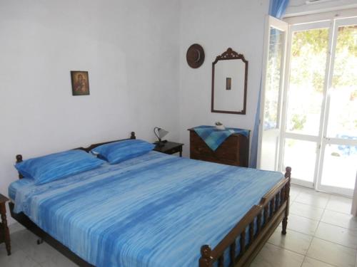 a bedroom with a bed with blue sheets and a window at Villetta IRENULLA in Posidhonía