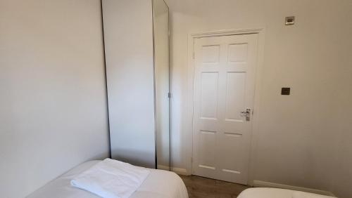 ロンドンにあるGarland Spacious 4 Bedroom House With Garden And Parkingのドア、ベッド、鏡付きの部屋