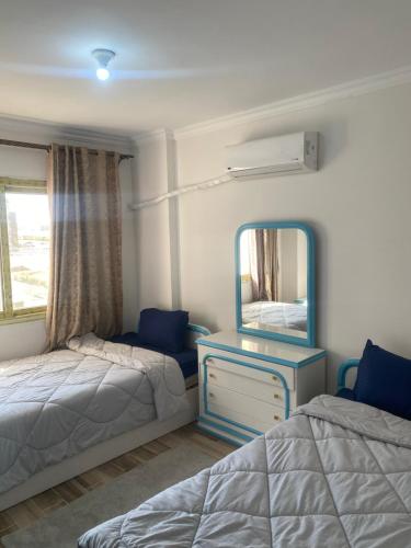 a bedroom with two beds and a mirror at شقق فندقية راقي in Sheikh Zayed