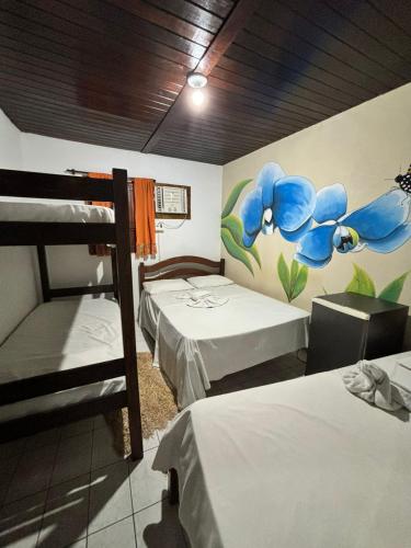 a room with two beds and a mural of flowers at Pousada Vida Mansa in Porto De Galinhas