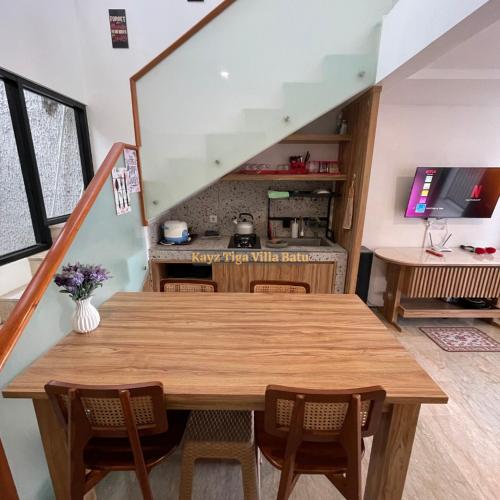 a dining room with a wooden table and a kitchen at Kayz Tiga Villa Batu Private Pool Aesthetic in Tlekung
