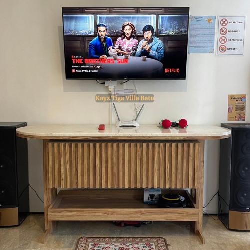 a tv on a wall with a wooden table with a television at Kayz Tiga Villa Batu Private Pool Aesthetic in Tlekung