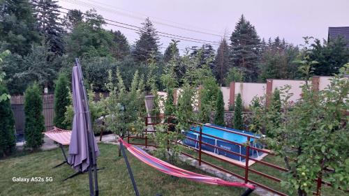 a hammock and an umbrella in a garden at Pensiunea Casuta cu Trandafiri 2 in Slănic
