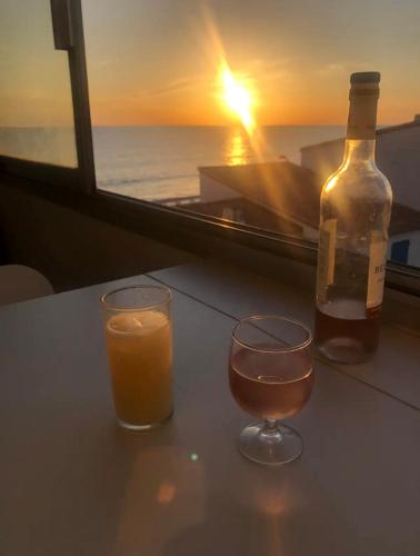 une bouteille de vin et deux verres sur une table avec un coucher de soleil dans l'établissement Studio 61, vue mer, wifi, parking privé, à Saint-Hilaire-de-Riez