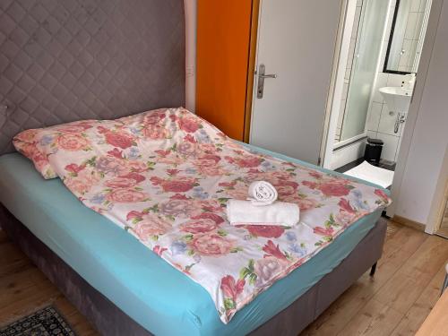 a bed with a flowered blanket on top of it at Sobe Stremljan Ljubljana in Medvode