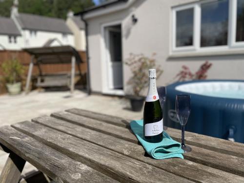 a bottle of wine sitting on a wooden table with a glass at Large New Studio Apartment and Hot Tub - Private Hideaway in the Brecon Beacons in Bwlch
