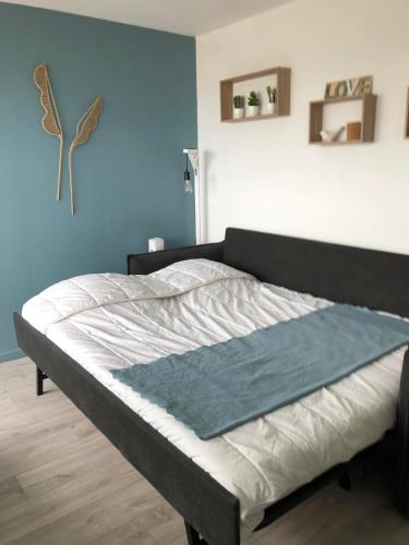 Ce lit se trouve dans une chambre dotée d'un mur bleu. dans l'établissement Studio 61, vue mer, wifi, parking privé, à Saint-Hilaire-de-Riez