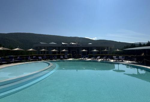 a large swimming pool with chairs and umbrellas at Aar Hotel & Spa Ioannina in Ioannina