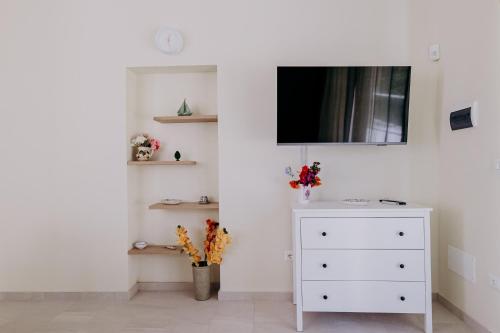 a bedroom with a dresser and a tv on a wall at Casa Zefiro Fontane Bianche in Fontane Bianche