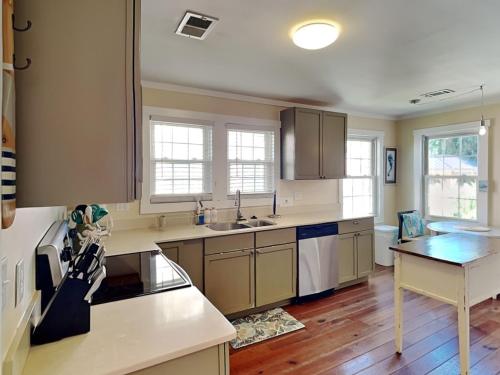 een keuken met witte kasten en een tafel. bij CB Sunshine Cottage in Carolina Beach