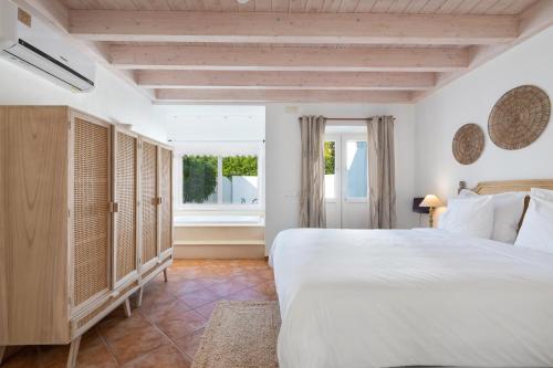 a bedroom with a large bed and a window at Casa Flor de Sal in Moncarapacho