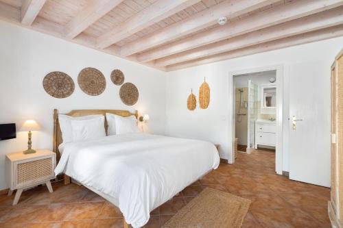 a bedroom with a large white bed with white sheets at Casa Flor de Sal in Moncarapacho