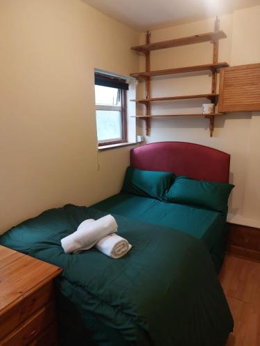a bedroom with a green bed with two towels on it at Cosy Greener Private room in Pinner