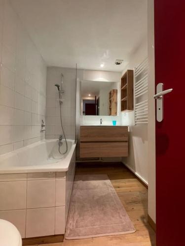 une salle de bain blanche avec une baignoire et un lavabo dans l'établissement T2 classé 3 étoiles coeur de village et Piscine ext, à Saint-Lary-Soulan