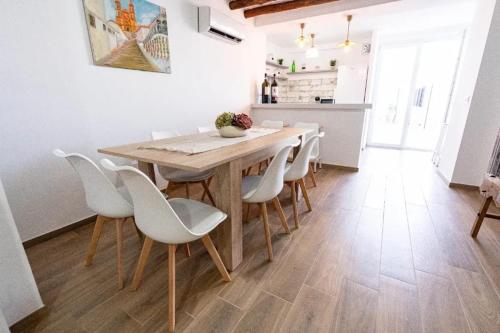 a dining room with a wooden table and white chairs at Spacious house in Olvera with private pool in Olvera