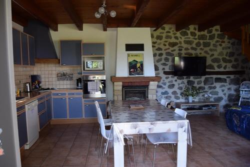 une cuisine avec une table et des chaises ainsi qu'une cheminée dans l'établissement Gîte 4 personnes dans le Cantal Animaux bienvenus, à Lascelle